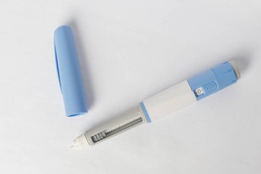 Beyaz arka planda asılı duran antidiyabetik ilaç ya da anti-obezite ilacı için enjektörler ya da dozu arttırıcı kalemler
