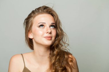 Makyajlı, uzun dalgalı saçlı, yakın plan portresi olan neşeli genç bayan. Güzel kadın.