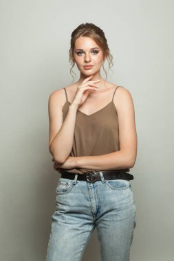 Beyaz stüdyo arka planında duran açık renk ceketli çekici, yetişkin bir kadın.