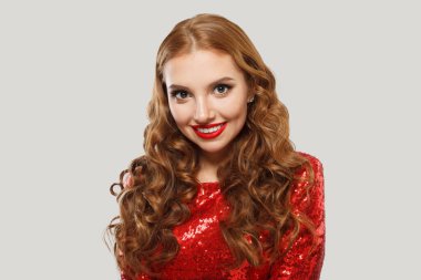 Uzun kıvırcık kahverengi saçlı, stüdyo duvarına poz veren genç, güzel bir kadın.