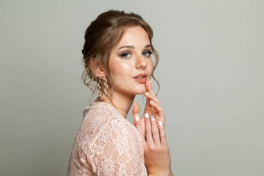 Çekici, zarif bir kadın. Taze tenli, updo saçlı ve beyaz arka planda makyajlı. Güzel yüz yakın plan