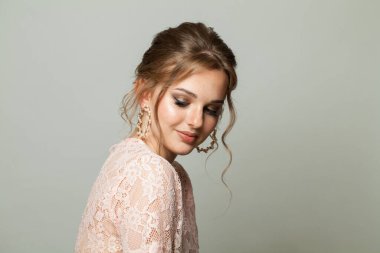 Kusursuz zarif bir kadın. Taze tenli, updo saçlı ve beyaz arka planda makyaj yapan. Güzel yüz yakın plan