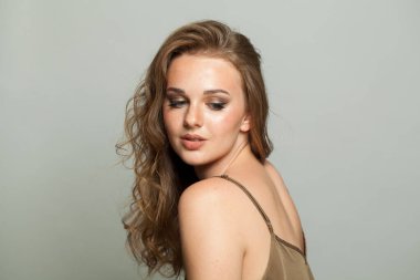 Makyajlı, uzun dalgalı saçlı, yakın plan portresi olan genç bir bayan. Güzel kadın.