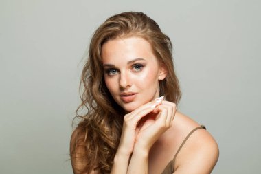 Çekici bir kadın yüzü. Makyajlı bir kadın, kıvırcık saç stili ve beyaz arka planda yeni bir ten.