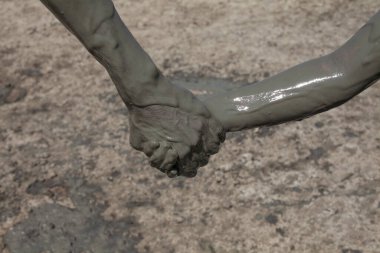 Hands of father and daughter on mud geyser resort close-up outdoors clipart