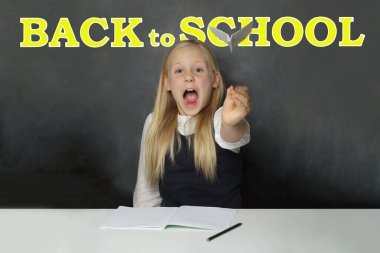 Tahta arka planda sarı okula dönüş yazısı olan heyecanlı liseli kız öğrenci. Eğitim kavramı