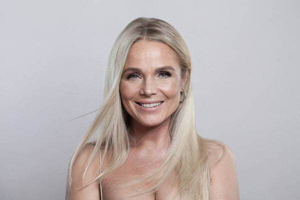 Pretty healthy blonde mid adult mature woman looking at camera on white background. Mature lady portrait. Healthy face, skin care beauty, middle age skincare cosmetic and cosmetology concept