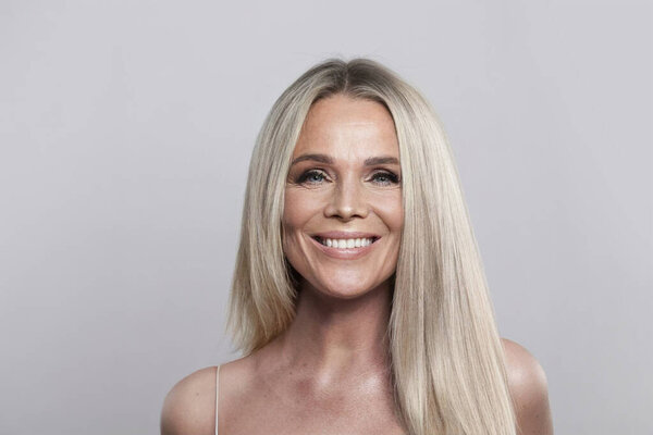 Joyful mature model woman looking at camera, studio portrait. Beauty, cosmetic, anti-aging and skincare concept