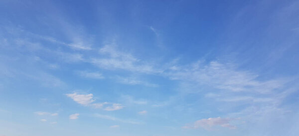 White clouds of different shapes in the blue sky, windy spring background