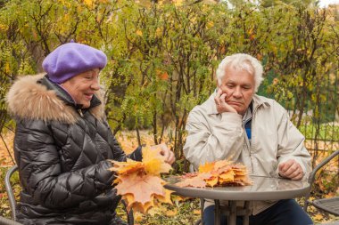 Yaşlı çift sonbahar parkında bir bankta dinleniyor.