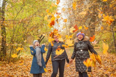 Büyükanne, anne ve kızı sonbahar parkında yürüyor. Mutlu aile