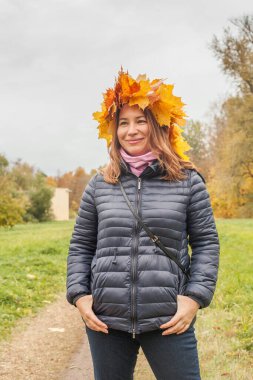 Sarı yapraklı çekici kadın, sonbahar arka planında açık havada çelenk, portre.