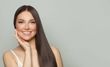 Doğal makyajlı ve uzun düz kahverengi saçlı neşeli genç kadın modeli. Yüz bakımı, kozmetoloji, cilt bakımı ve güzellik salonu konsepti