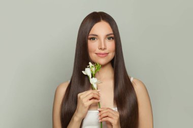 Doğal makyajlı ve uzun düz kahverengi saçlı bir kadın model. Yüz bakımı, kozmetoloji, cilt bakımı ve güzellik salonu konsepti