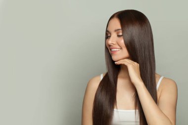 Doğal makyajlı ve uzun düz kahverengi saçlı mükemmel bir genç kadın modeli. Yüz bakımı, kozmetoloji, cilt bakımı ve güzellik salonu konsepti