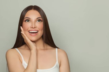 Doğal makyajlı ve uzun düz kahverengi saçlı bir kadın modeli. Yüz bakımı, kozmetoloji, cilt bakımı ve güzellik salonu konsepti