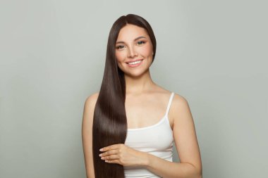 Doğal makyajlı ve uzun düz kahverengi saçlı çekici bir kadın modeli. Yüz bakımı, kozmetoloji, cilt bakımı ve güzellik salonu konsepti