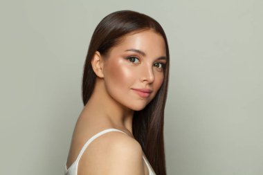 Doğal makyajlı ve uzun düz kahverengi saçlı bir kadın modeli. Yüz bakımı, kozmetoloji, cilt bakımı ve güzellik salonu konsepti