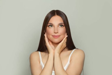 Doğal makyajlı ve uzun düz kahverengi saçlı sağlıklı bir kadın modeli. Yüz bakımı, kozmetoloji, cilt bakımı ve güzellik salonu konsepti