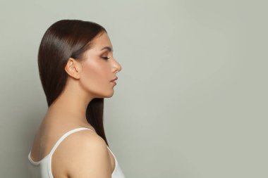 Doğal makyajlı ve uzun düz kahverengi saçlı genç kadın modeli profili. Yüz bakımı, kozmetoloji, cilt bakımı ve güzellik salonu konsepti