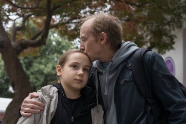 Mutlu baba dışarıda kızını kucaklıyor ve öpüyor.