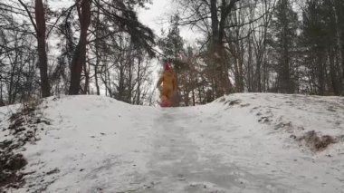 Çocuk kar tepeciğindeki buzun üzerinde kayıyor.