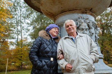 Son sınıf çifti, sonbahar parkında romantik bir yürüyüş yapıyor.