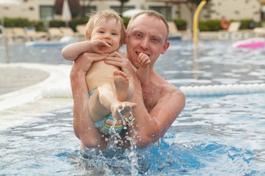 Babayla gülen bebek. Küçük kız babasıyla havuzda eğleniyor.