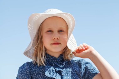 Mavi gökyüzü resmine karşı yaz şapkalı sarışın kız.