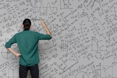 Bir kadın bir duvarın yanında duruyor, üzerinde matematiksel denklemler, grafikler ve grafikler var. Fikir üretme ve düşünme kavramı