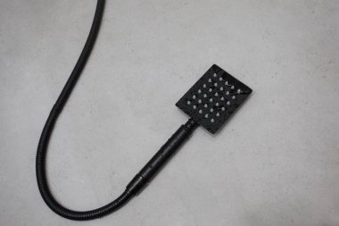 Banyo içi arka plan, gri seramik fayanslarda siyah duş başlığı.