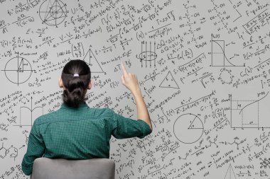 Matematiksel denklemlerin, grafiklerin ve grafiklerin çizildiği bir duvarın yanında oturan bir kadın. Fikir üretme ve düşünme kavramı