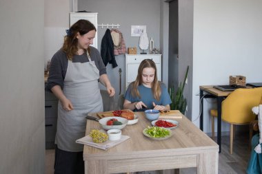 Sevgi dolu anne ve kız mutfakta lezzetli yemekler hazırlıyorlar. Aile bir arada. Anne kız çocuğuna yemek yapmayı öğretiyor.