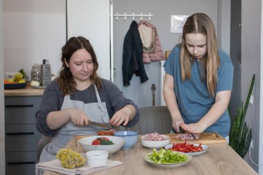 Sağlıklı anne ve kız mutfakta lezzetli yemekler hazırlıyorlar. Aile bir arada. Anne kız çocuğuna yemek yapmayı öğretiyor.