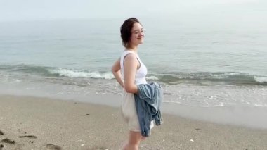 Genç bir kadın kumda yürüyor.