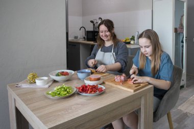 Mutlu gülümseyen anne ve sevgi dolu çocuk evde birlikte vakit geçiriyorlar. Sağlıklı yemek ve yemek hazırlığı.