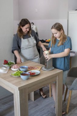 Anne ve kızının evde portresi mutfakta lezzetli yemekler hazırlıyor. Aile bir arada. Anne kız çocuğuna yemek yapmayı öğretiyor.