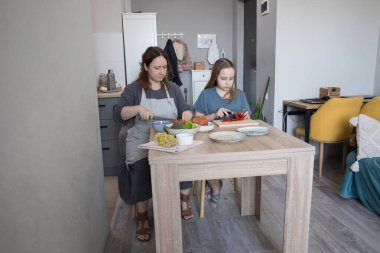 Anne ve kızı mutfakta birlikte yemek hazırlıyorlar..