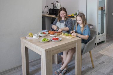 Gülümseyen anne ve küçük kızı birlikte salata hazırlıyorlar..