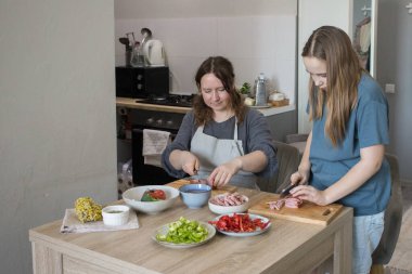 Güzel kız ve annesi birlikte ev mutfağında yemek pişiriyorlar, aile portresi yapıyorlar..