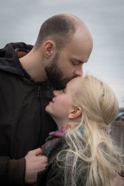 Uzun sarı saçlı neşeli genç kadın ve deniz kenarında öpüşen erkek çift..