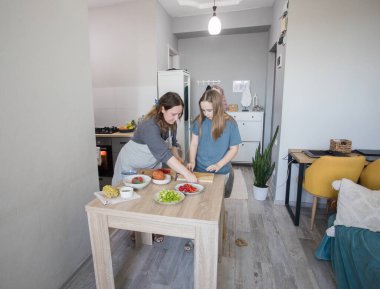 Genç kız annesinden yemek hazırlamayı öğreniyor..