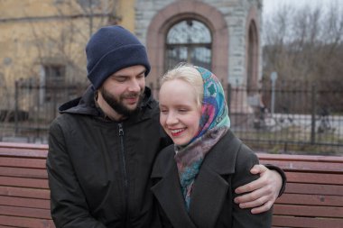 Tebessüm eden kadın ve adam bankta oturuyor. Erkek arkadaş ve kız arkadaş dışarıda. Mutlu çift