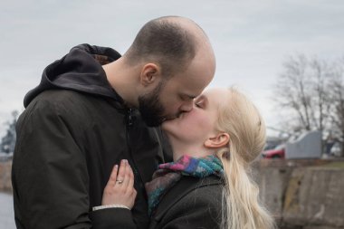 Sevecen erkek ve kadın çift sahilde öpüşürken birbirlerine sarılıyorlar.