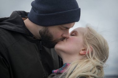 Yakışıklı erkek ve kadın çift sahilde öpüşürken sarılıyorlar.