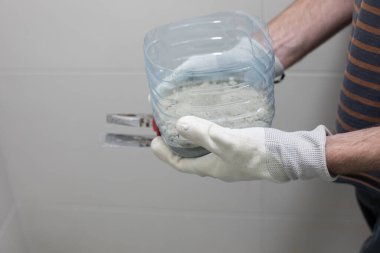 Tuvalet tamiri için çimento yapıştırıcısı, erkeklerin elinde.