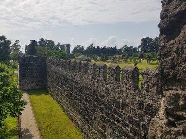Güneşli bir günde gökyüzünde bulutlar olan antik Roma kalesinin taş duvarı.