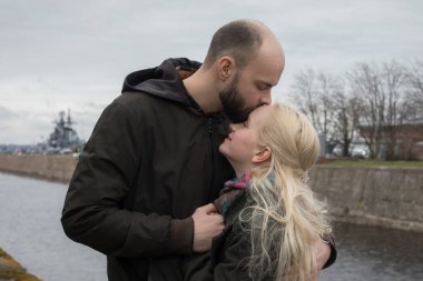 Uzun sarı saçlı mükemmel kadın ve deniz kenarında öpüşen erkek çift.