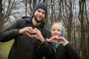 Genç çift parktaki elleriyle kalp yapıyor.