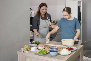 Neşe dolu bir aile. Anne ve kızı birlikte mutfakta pizza pişiriyorlar.